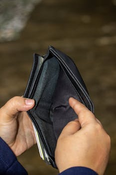 A close-up image of an empty leather wallet held by two hands, symbolizing financial challenges.