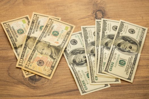 A collection of US dollar bills arranged on a wooden surface, showcasing currency denominations.