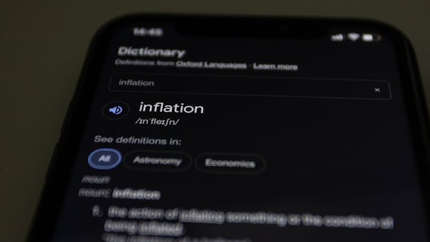 Close-up of a smartphone screen showing the word inflation defined in a dictionary app.